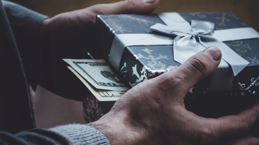 A man handing a gift box with money poking out